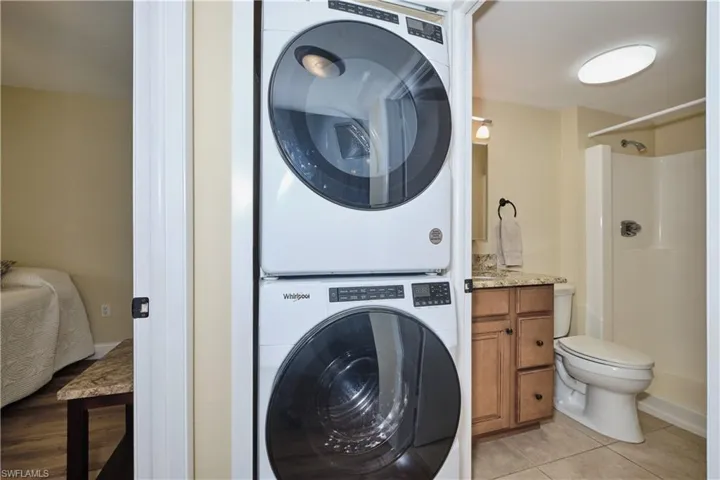 Washroom with newer full-sized stacked washer and clothes dryer.