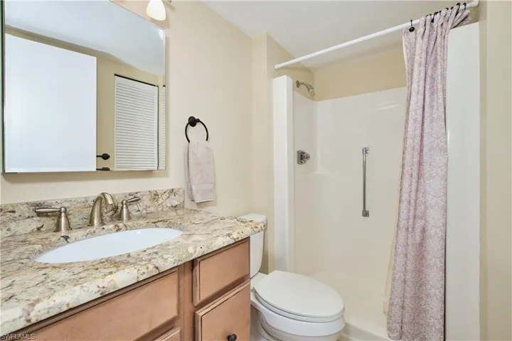 Bathroom featuring vanity with granite tops, a linen closet and a stall shower