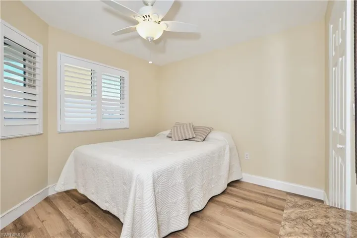 Bedroom with light wood-style flooring and lighted ceiling fan.