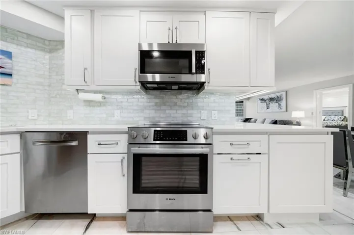 Kitchen with white cabinets, stainless steel appliances, and decorative backsplash