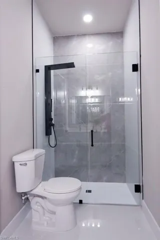 Bathroom featuring baseboards and a marble finish shower
