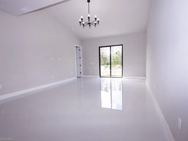 Empty room with tile patterned flooring, a chandelier, and vaulted ceiling
