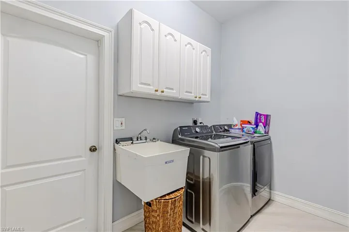 Laundry room featuring washer, dryer, cabinets, utility sink and baseboards