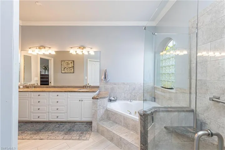 Bathroom featuring ornamental molding, a garden tub, double vanity and a shower stall