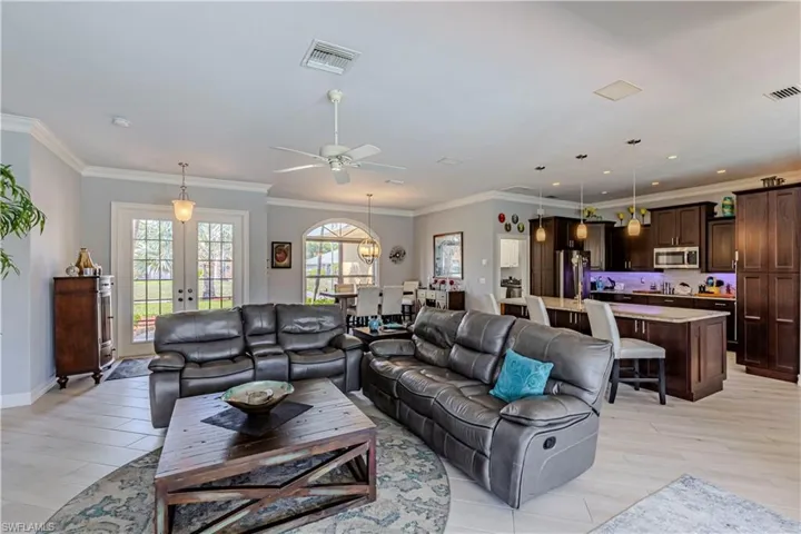 Living area with ceiling fan, French doors, light wood-tile flooring, baseboards and recessed lighting