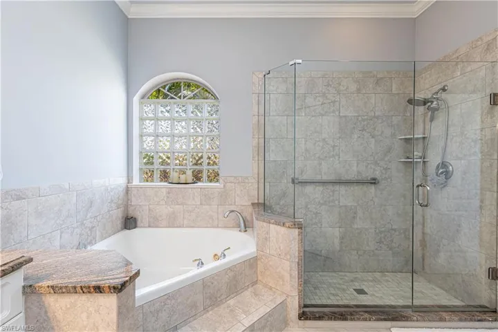Full bathroom featuring a garden tub, ornamental molding and a shower stall