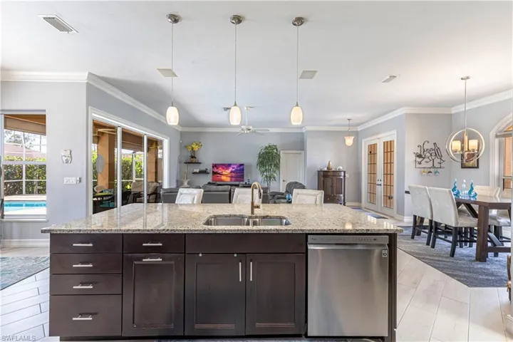 Kitchen featuring dishwasher, a sink, dark brown cabinetry, baseboards and crown molding