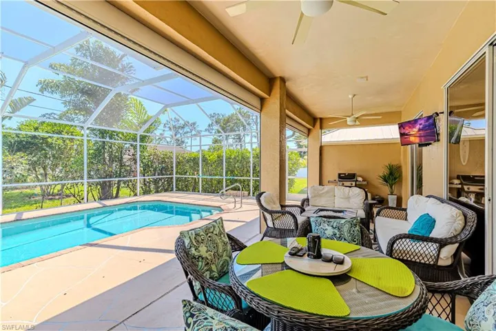 Outdoor pool featuring 2 ceiling fans, an outdoor hangout area, a patio, and screen enclosure