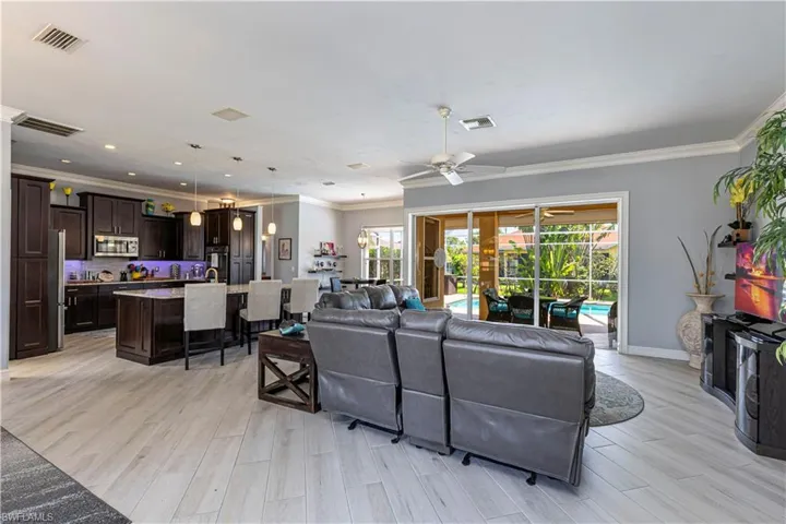 Living room with ceiling fan, crown molding, light wood-tile flooring and baseboards
