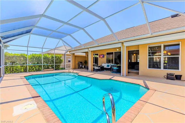 View of pool featuring a patio area, ceiling fans, outdoor lounge area and screen enclosure