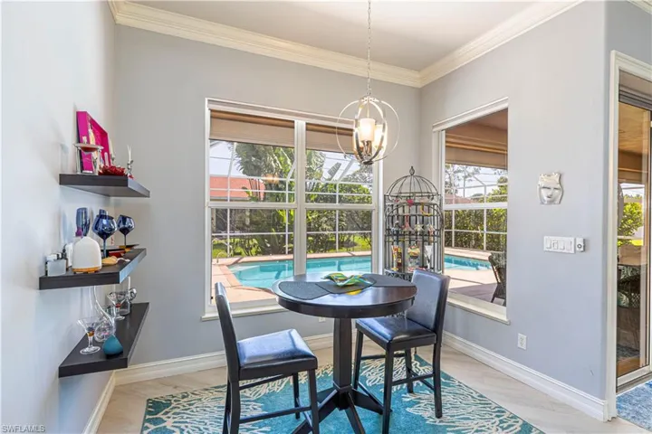 Nook featuring a chandelier, healthy amount of natural light, light tile colored floors and ornamental molding