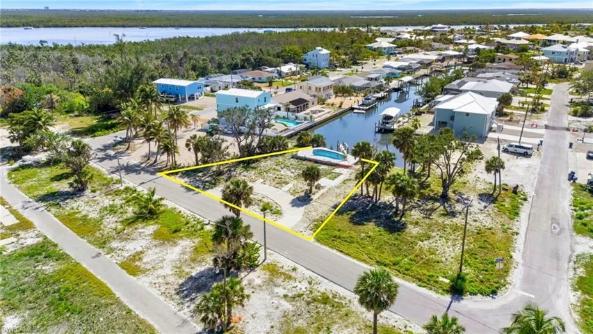 Aerial view of residential area featuring property parcel outlined and a large body of water  - Virtually Edited Image