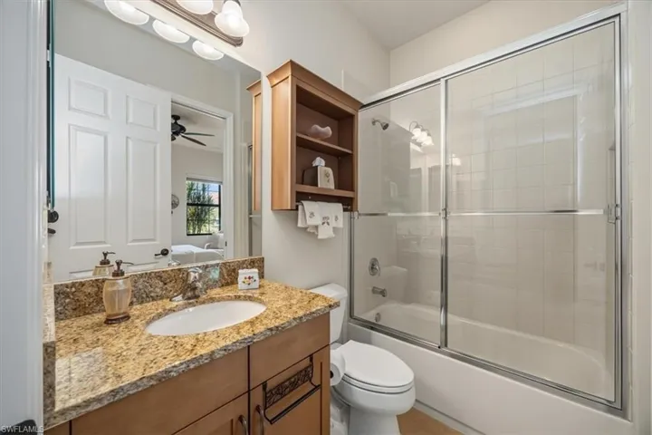 Bathroom featuring bath / shower combo with glass door, vanity, ensuite bathroom, and a ceiling fan