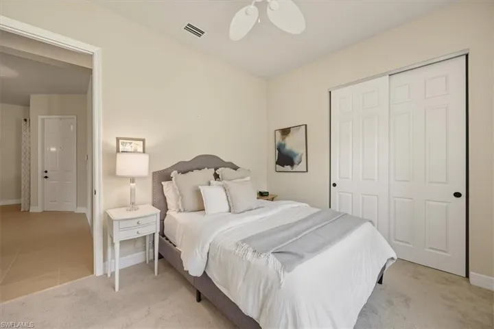 Bedroom with light carpet, a closet, ceiling fan, and light tile patterned flooring