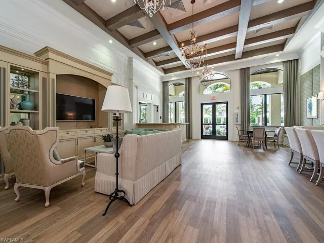 Living room featuring beamed ceiling, coffered ceiling, french doors, wood finished floors, and a chandelier