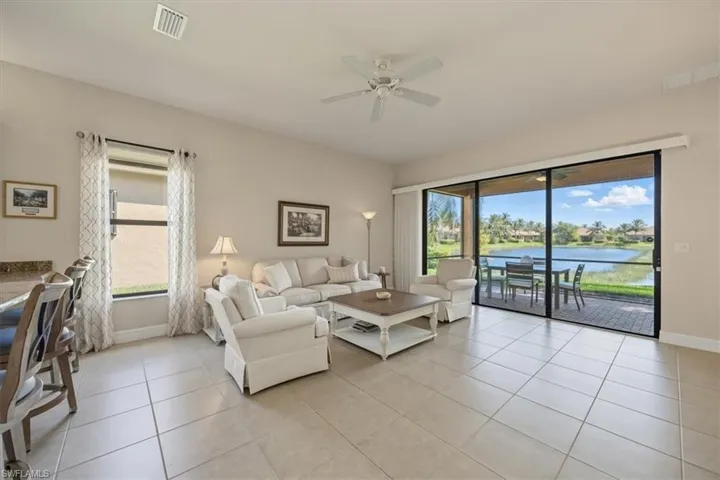 Living room featuring light tile patterned floors, ceiling fan, and a water view