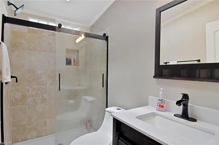 Bathroom with a shower stall, vanity, and crown molding