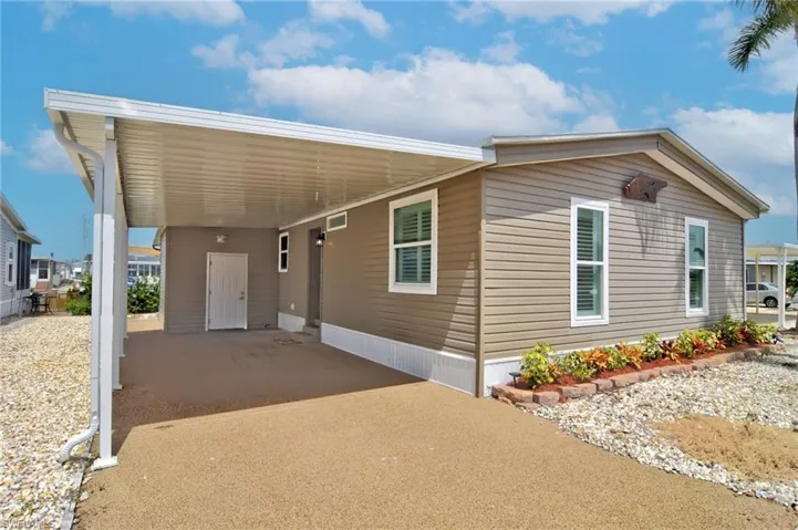 Manufactured / mobile home featuring an attached carport, a patio, and driveway