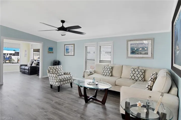 Living area featuring crown molding, wood finished floors, and ceiling fan