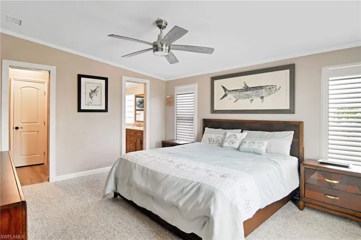 Bedroom with ornamental molding, carpet floors, ceiling fan, and connected bathroom
