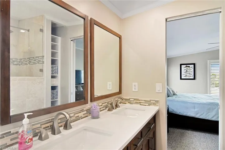 Bathroom with backsplash, crown molding, double vanity, connected bathroom, and a stall shower