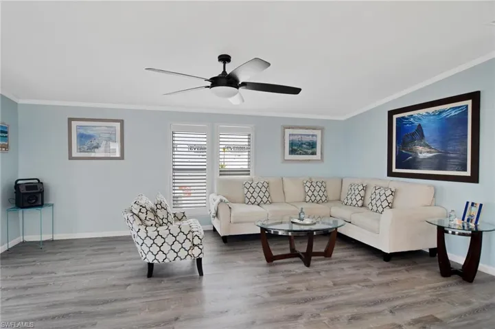Living room featuring crown molding, light wood-style flooring, and a ceiling fan