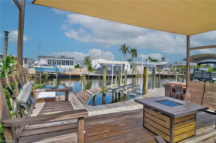 Dock area with a residential view, a water view, boat lift, and an outdoor fire pit