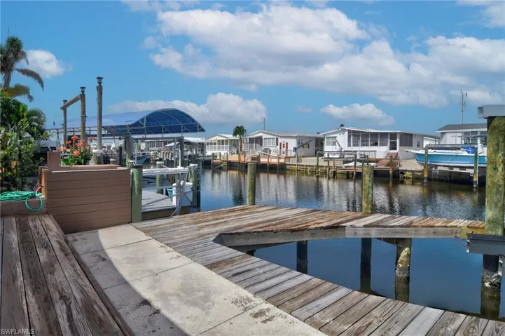 Dock with boat lift, a water view, and a residential view