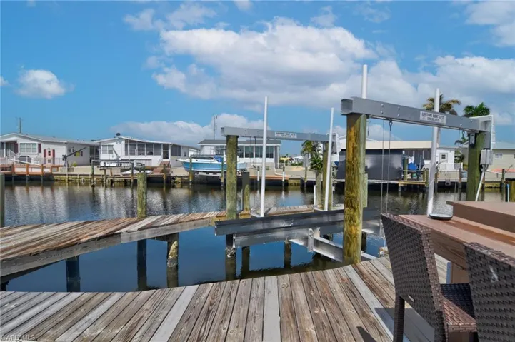 Dock featuring boat lift, a water view, and a residential view