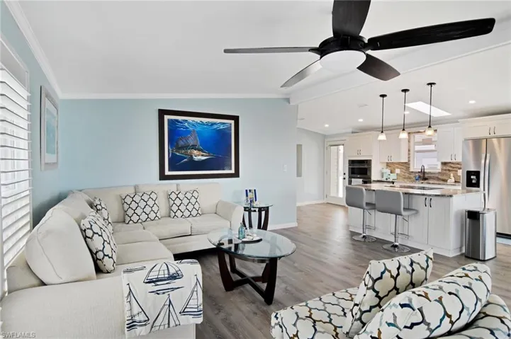 Living room featuring a ceiling fan, light wood-type flooring, and crown molding