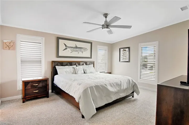 Bedroom with ornamental molding, light carpet, and a ceiling fan