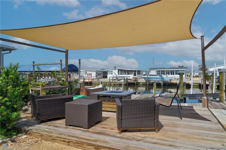 Deck featuring a dock, boat lift, a water view, and an outdoor fire pit