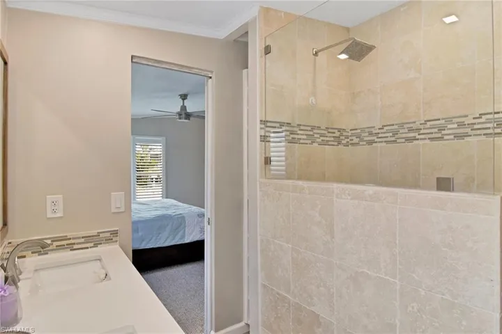 Ensuite bathroom with a stall shower, ornamental molding, vanity, and a ceiling fan