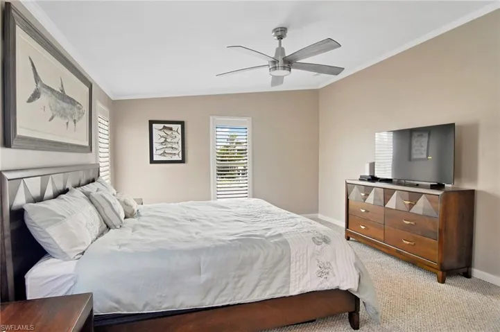 Carpeted bedroom featuring crown molding and a ceiling fan