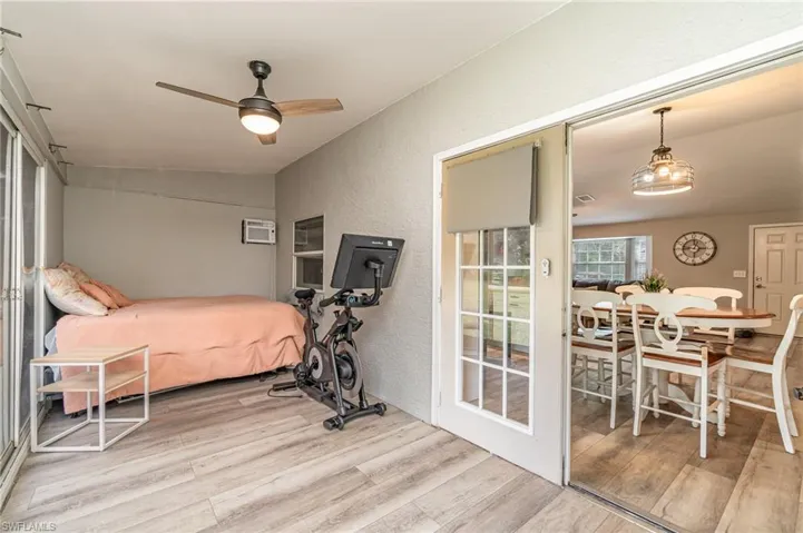 Currently used as a 4th bedroom featuring a wall unit AC, ceiling fan, and light hardwood / wood-style floors