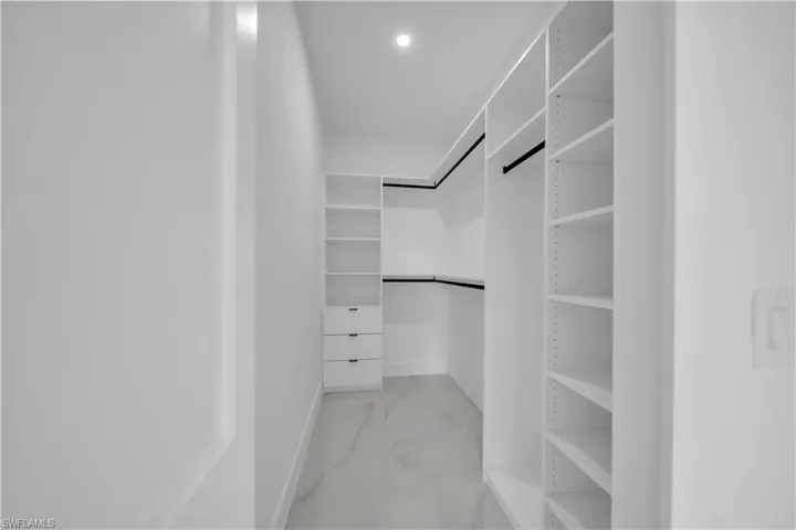 Spacious closet featuring light marble finish flooring