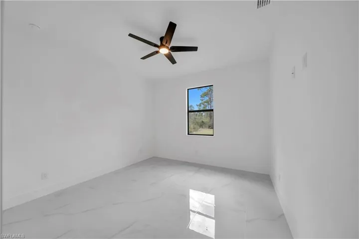 Empty room with light marble finish floors and a ceiling fan