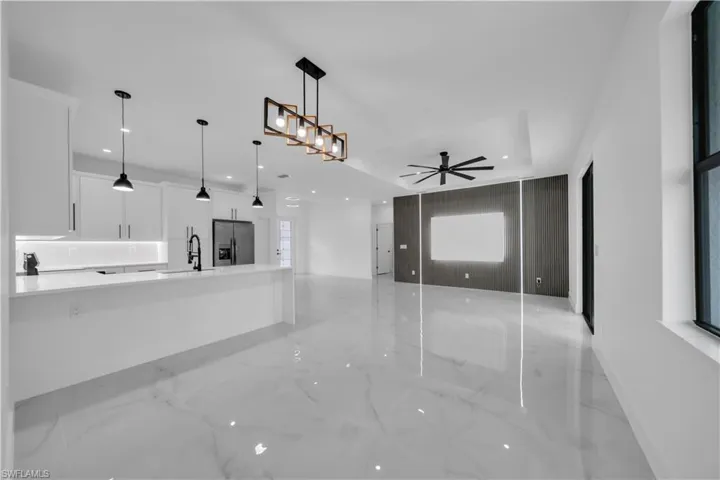 Unfurnished living room featuring light marble finish flooring, a ceiling fan, and recessed lighting