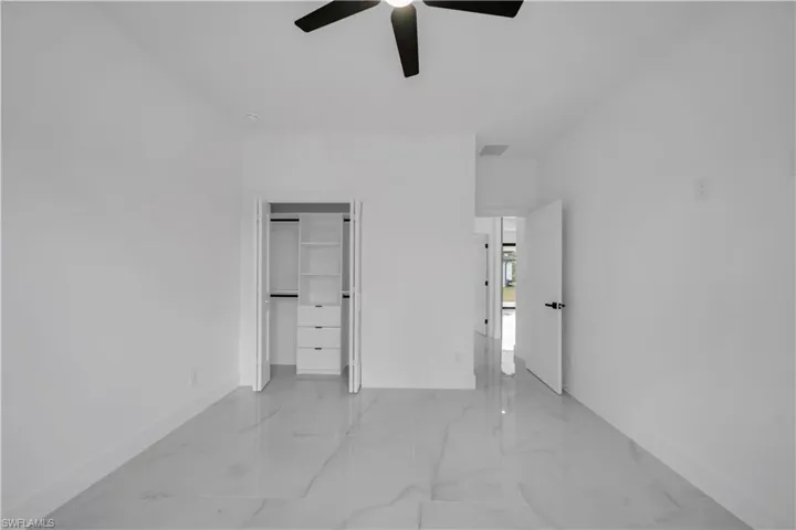 Unfurnished bedroom with light marble finish flooring, a ceiling fan, and a closet