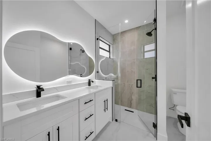 Bathroom featuring a stall shower, double vanity, and recessed lighting
