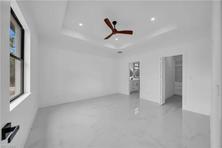 Unfurnished bedroom with a walk in closet, ceiling fan, recessed lighting, and ensuite bath
