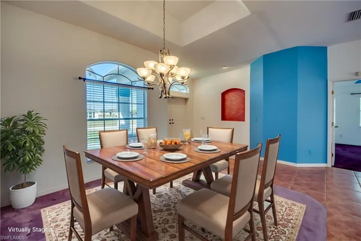 Tiled dining area with lofted ceiling and an inviting chandelier