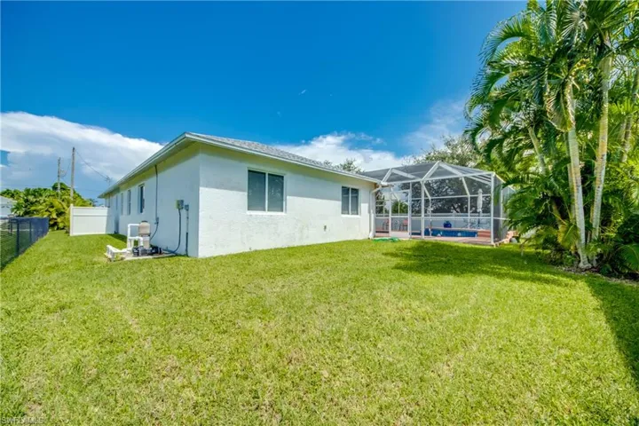 Back of property with a pool, a lanai, and a lawn
