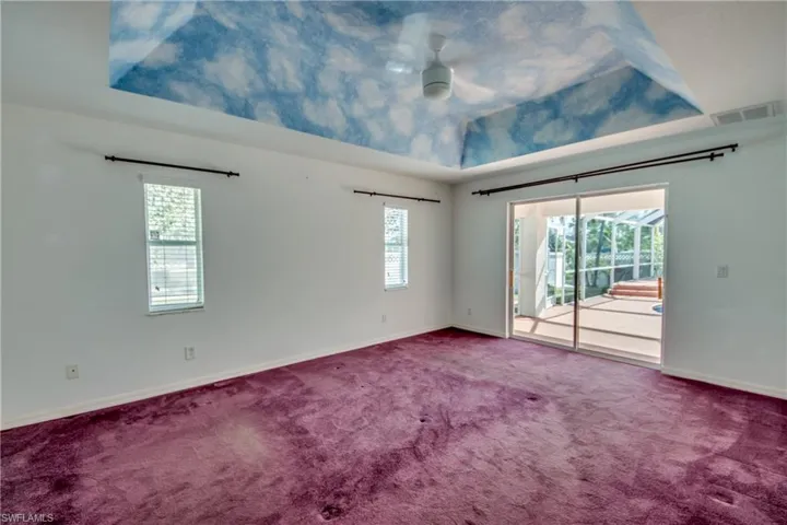 Carpeted empty room featuring ceiling fan and a tray ceiling