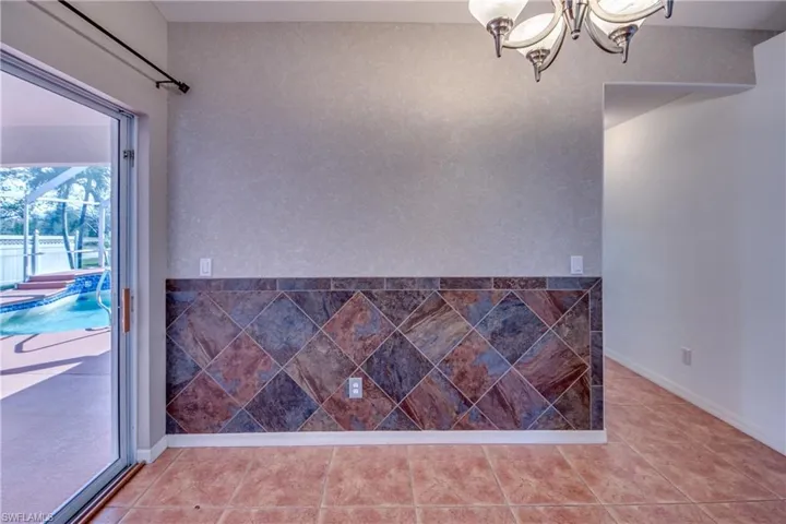 Tiled spare room with a notable chandelier