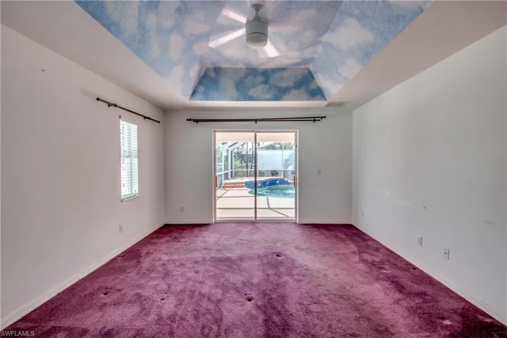 Carpeted spare room featuring ceiling fan and a raised ceiling