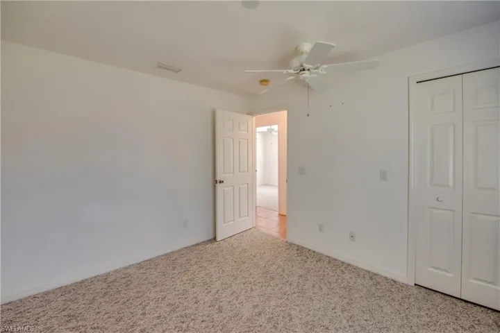 Unfurnished bedroom featuring light colored carpet, a closet, and ceiling fan