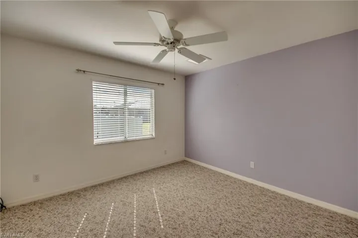 Carpeted empty room featuring ceiling fan