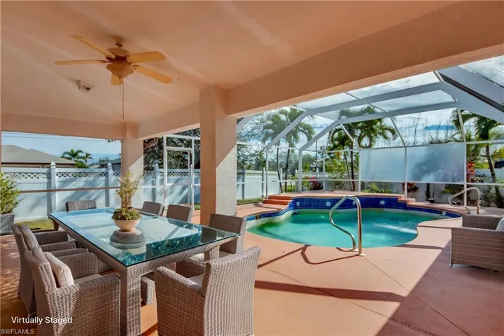View of pool with a patio, ceiling fan, and glass enclosure
