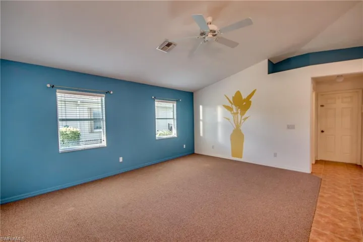 Carpeted spare room with lofted ceiling and ceiling fan